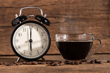 A cup of coffee and coffee bean with clock on wooden table background.