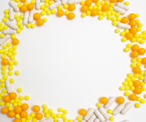 colorful pills for viral diseases in circle frame with copyspace for text. Prevention of influenza, coronavirus, covid-19. yellow, orange vitamins on white background. medical healthcare concept