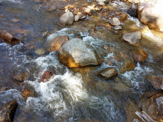 The rocks in the mineral water flow naturally through the Chae Son National Park, Lampang, Thailand.