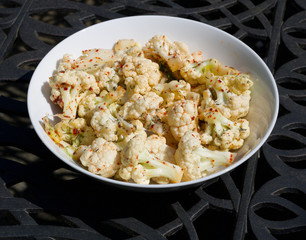 A bowl of raw cauliflower in round dish sprinkled with chilli