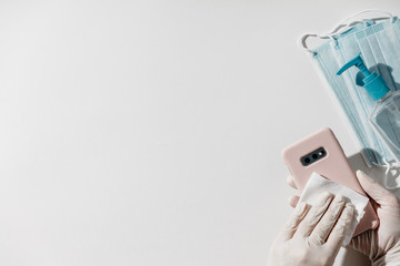 Coronavirus global epidemic. Woman in latex gloves disinfecting phone with antiseptic wet wipe....