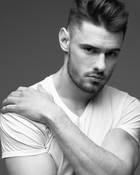 young man with a beard. A man in a t-shirt. Male portrait on a gray background. Stylish man. black and white photo. Sports man. male fitness model. studio portrait	
