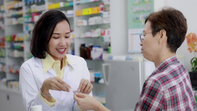asian female pharmacist and patients talking and smiling detail medicine in pharmacy store Thailand 