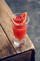 Strong red cocktail in shots on the rustic background. Selective focus. Shallow depth of field.