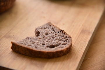 Fototapeta na wymiar A fresh crusty loaf of homemade bread. Homemade rustic sour bread on a wooden chopping board. Slice of brown bread. Sliced bread. 