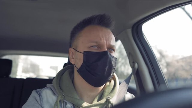 The driving car man wearing protection mask on the face sitting in the car in disposable gloves during the coronavirus pandemic. Prores 422