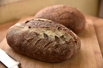 A fresh crusty loaf of homemade bread. Homemade rustic sour bread on a wooden chopping board.
Brown bread