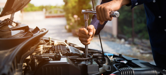 Auto mechanic hands using wrench to repair a car engine. concepts of car insurance support and...
