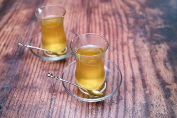 Two cups of traditional Turkish fruit tea on a wooden table with intentional selective and close focus, and shallow depth of field
