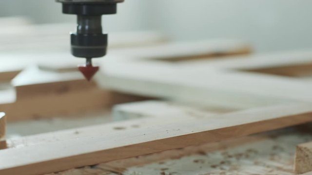 In the woodworkers shop the cnc drill is drilling a pattern in to the wooden plank, close up footage.