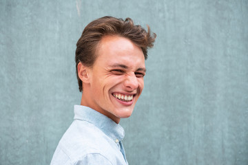 side portrait young man smiling by green wall