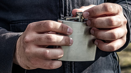 homeless fingers close up. hands of a dirty adult man. A homeless person is about to drink water from an aluminum flask.