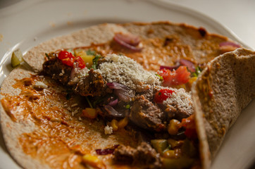 
kebab in a tortilla with sauce and vegetables