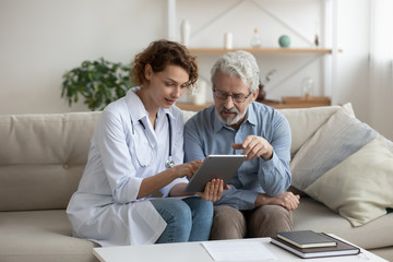 Female professional doctor showing medical test result explaining prescription using digital tablet...