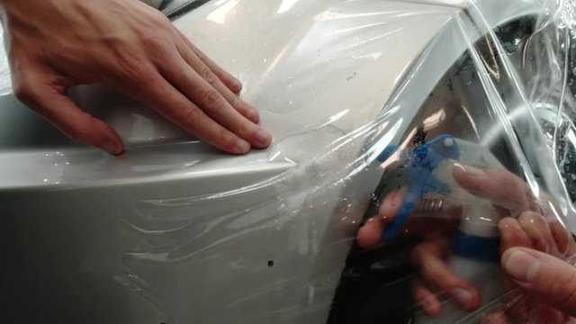Close up to PPF installation process on silver sports car. PPF is a Paint Protection Film which protect paint from scratches and stone chips.