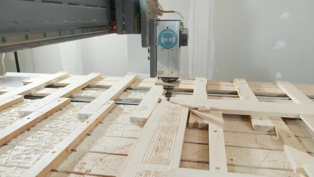 In the woodworkers shop the cnc drill is drilling a pattern in to the wooden plank