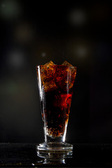 Glass cola with ice on a black background a glass of  cola in a popular bar. Pint of foamy drink in a restaurant