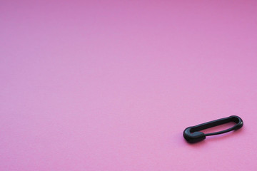 Black closed safety pin on a bright pink background
