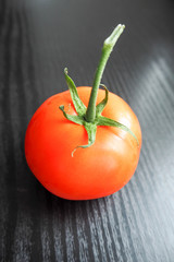 red round tomato with a green tail on a dark background