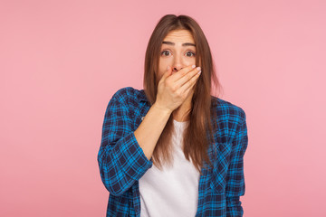 I won't tell anyone! Portrait of frightened scared girl in checkered shirt covering mouth with...