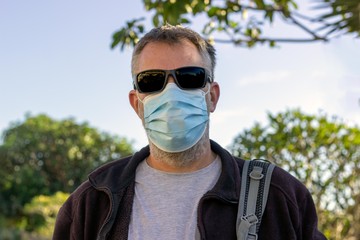 middle aged bearded man wearing face mask and sunglasses