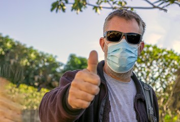 bearded man wearing a face mask with the thumbs ups