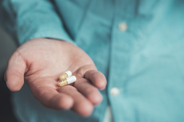 Medicament or cure concept. Close up of male hand with pills.