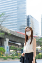Fototapeta premium COVID-19 Pandemic Coronavirus Asian Woman in city street going to work. She wearing face mask protective for spreading of disease virus. 