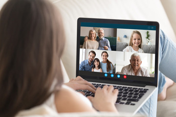 Young woman relax on couch at home talk on video call on laptop with relatives, millennial girl rest sit on sofa speak chat with family, have webcam conference, technology concept