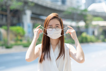 Portrait closeup of Asian female putting a mask on her face. Protects against the coronavirus or Covid-19 quarantine 