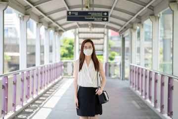 COVID-19 Pandemic Coronavirus Asian Woman in city street going to work. She wearing face mask protective for spreading of disease virus. 