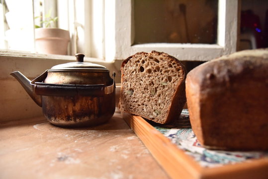 A fresh crusty loaf of homemade bread. Homemade rustic sour.
Brown bread. Different types of loaves. Sliced Bread. Atmosphere image of a countryside style kitchen.