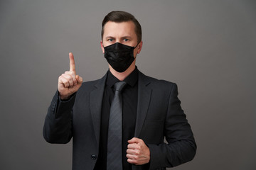 Businessman with surgical medical mask pointing with finger.