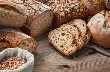 Many different handmade, freshly baked breads on wooden table with copy space
