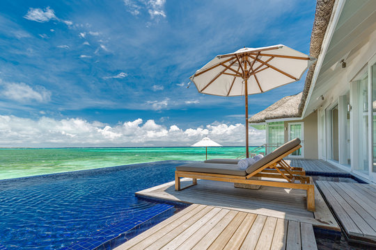 Luxury beach resort, water villa bungalow near endless pool over sea. Summer tropical island, travel vacation concept. Beach chairs with umbrella, luxurious landscape sunny weather, exotic nature view
