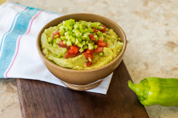 Guacamole in bowl on wooden board and marble table. Real food at home background 