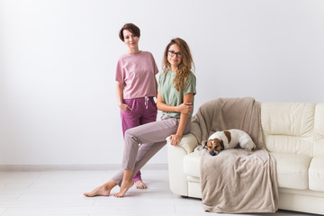 Two female friends or sisters at home with their cute dog. Quarantine, isolation, coronavirus pandemic world. Stay at home.