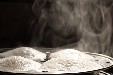 Steaming hot idly in the making with nice vapour
