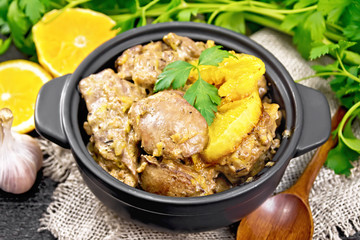 Liver with oranges in pan on board