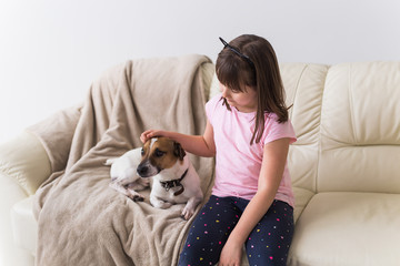 Child girl with cute dog jack russell terrier on the couch. Pets , children and home concept.