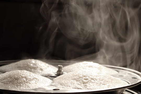Steaming hot idly in the making with nice vapour
