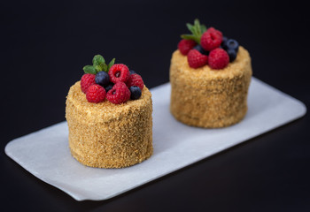 Small round cakes with berries on a black background