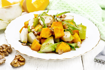 Salad of pumpkin and pear in plate on board