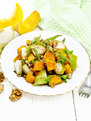 Salad of pumpkin and pear in plate on light wooden board