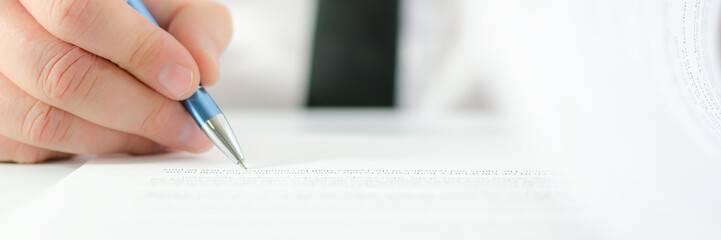 Wide view of businessman flipping a page of contract and signing it with a pen