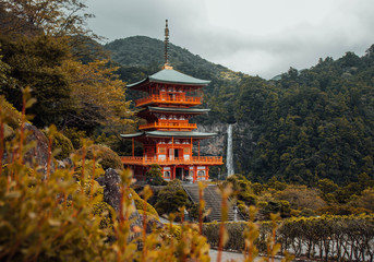 Fototapeta premium Mystical view over the ancient building and the huge waterfall at Kumano Nachi taisha, on the famous stone path Kumano Kodo pilgrimage route