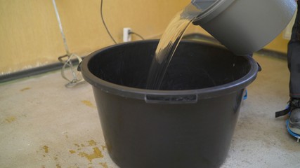 Pour water into a bucket to mix the solution. Construction machinery working pouring water into...