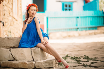 Redhead moldavian girl dressed in blue dress sitting on a stone stairs