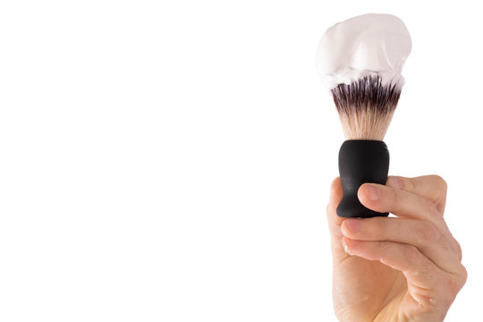 male hand holds a shaving brush on which foam