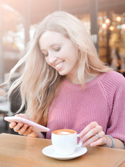 Beautiful young woman posing in caffeine with cup of latte.